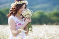 A pregnant woman in a field with a bouquet of white daisies Royalty Free Stock Photo