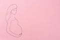 Pregnant woman figure drawn on pink background, top view with space for text. Surrogacy concept