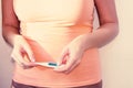 A pregnant woman in the first trimester wearing an orange T-shirt is holding a thermometer in her hands. Toning. IVF Royalty Free Stock Photo