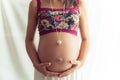 Pregnant woman with flower top and necklace.