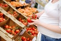 Pregnant woman in a food store or a supermarket choosing fresh organic tomatoes Royalty Free Stock Photo