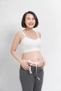 Pregnant woman gently embraces the belly tied with pink ribbon