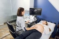 Pregnant woman getting ultrasound sonogram scan, while young concentrated female doctor obstetrician explains procedure