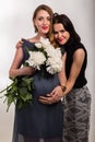 A pregnant woman with a girlfriend on a light background