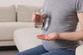 Pregnant woman with glass of water and pill at home, closeup Royalty Free Stock Photo
