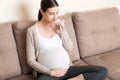 Pregnant woman with a glass of water sitting on sofa at the home Royalty Free Stock Photo