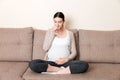 Pregnant woman with a glass of water sitting on sofa at the home Royalty Free Stock Photo