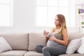 Pregnant woman with glass of water sitting on sofa Royalty Free Stock Photo