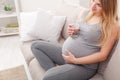 Pregnant woman with glass of water sitting on sofa Royalty Free Stock Photo