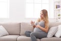 Pregnant woman with glass of water sitting on sofa Royalty Free Stock Photo