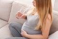 Pregnant woman with glass of water sitting on sofa Royalty Free Stock Photo