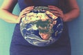 Pregnant woman with a globe instead of a belly. The concept of the miracle of life, the connection with the planet