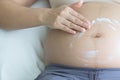 Pregnant woman hand lotion help skin belly on bedroom. Royalty Free Stock Photo