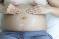 Pregnant woman hands lotion help skin belly on bedroom. Royalty Free Stock Photo