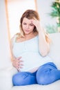 Pregnant woman having headache on couch