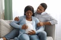 Pregnant woman having labor pains, sitting by husband on couch Royalty Free Stock Photo