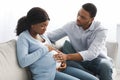 Pregnant woman having labor pains, sitting with husband on couch Royalty Free Stock Photo