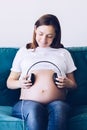 Pregnant woman with headphones at home