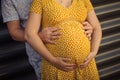 Pregnant woman held by her husband by her belly
