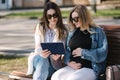 Pregnant woman with her best friend sitting in the park and looking for baby stroller using tablet. Two females in Royalty Free Stock Photo