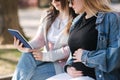 Pregnant woman with her best friend sitting in the park and looking for baby stroller using tablet. Two females in Royalty Free Stock Photo