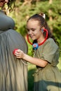 Pregnant woman with her daughter. Little girl excited about her coming sibling - listening to mother`s tummy Royalty Free Stock Photo