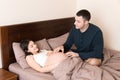 Pregnant woman with her husband in bed in the morning