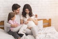 Pregnant Woman With Her Husband And Daughter On Bed At Home Royalty Free Stock Photo