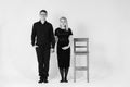Pregnant woman and her husband holding hands in black clothes on a white background. Black and white picture. Family concept.