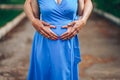 Pregnant woman and her husband holding hands on tummy in heart shape. Young loving family. New life concept Royalty Free Stock Photo