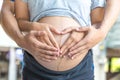 Pregnant Woman and Her Husband holding her hands in a heart shape on her baby bump Royalty Free Stock Photo