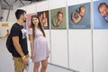 Pregnant woman and her husband look at a stand with pictures illustrate raising baby