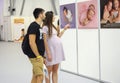 Pregnant woman and her husband look at a stand with pictures illustrate raising baby