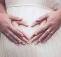 Pregnant woman and her husband making hand heart shape together