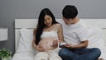 Pregnant woman and husband using fetal droppler device for listening baby heartbeat