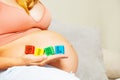 Pregnant woman hold color blocks making girl word