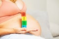 Woman hold girl word made out of blocks near belly