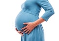 Pregnant woman hold hands on belly. Close-up.