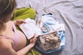 Pregnant woman holding baby bodysuit and packing maternity hospital bag. Beautiful mother during pregnancy waiting for baby Royalty Free Stock Photo