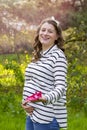 Pregnant woman holding baby shoes in her hands in a park Royalty Free Stock Photo