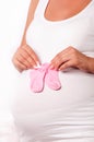 Pregnant woman holding baby socks on her pregnant belly Royalty Free Stock Photo