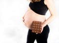 Pregnant woman holding a big dark chocolate bar. Gestational diabetes concept