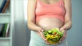 Pregnant woman holding bowl of vegetable salad rich in vitamins and nutrients