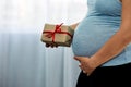 Pregnant Woman holding brown Gift Box in Her Cozy Bedroom with copy space