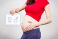 Pregnant woman holding card with female and masculine symbol. Expecting birth of girl or boy. Extending family Royalty Free Stock Photo