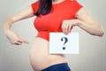 Pregnant woman holding card with question mark. Expecting birth of boy or girl. Extending family. Motherhood Royalty Free Stock Photo