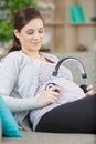 pregnant woman holding earphones near belly