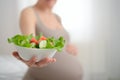 Pregnant woman is holding fresh vegetables in her hand. Concept of healthy eating during pregnancy. Royalty Free Stock Photo