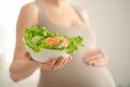 Pregnant woman is holding fresh vegetables in her hand. Concept of healthy eating during pregnancy. Royalty Free Stock Photo