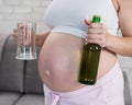 Pregnant woman holding glass and bottle of beer. Royalty Free Stock Photo
